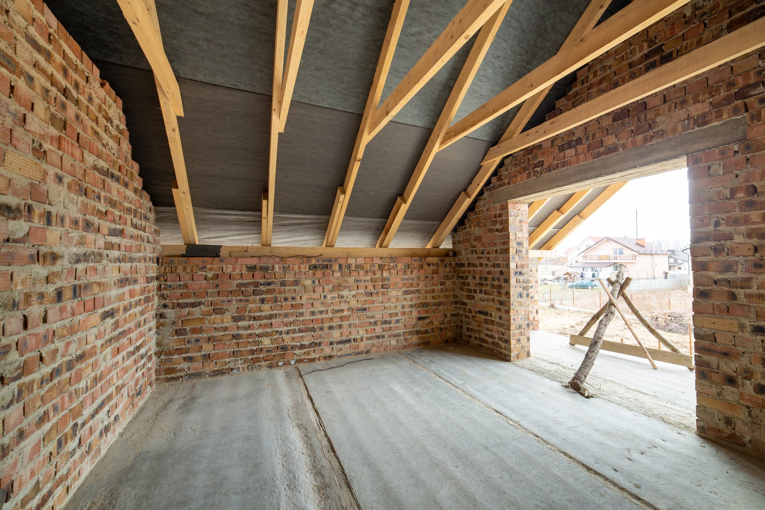 Unfinished interior with bare block walls and exposed roof timbers