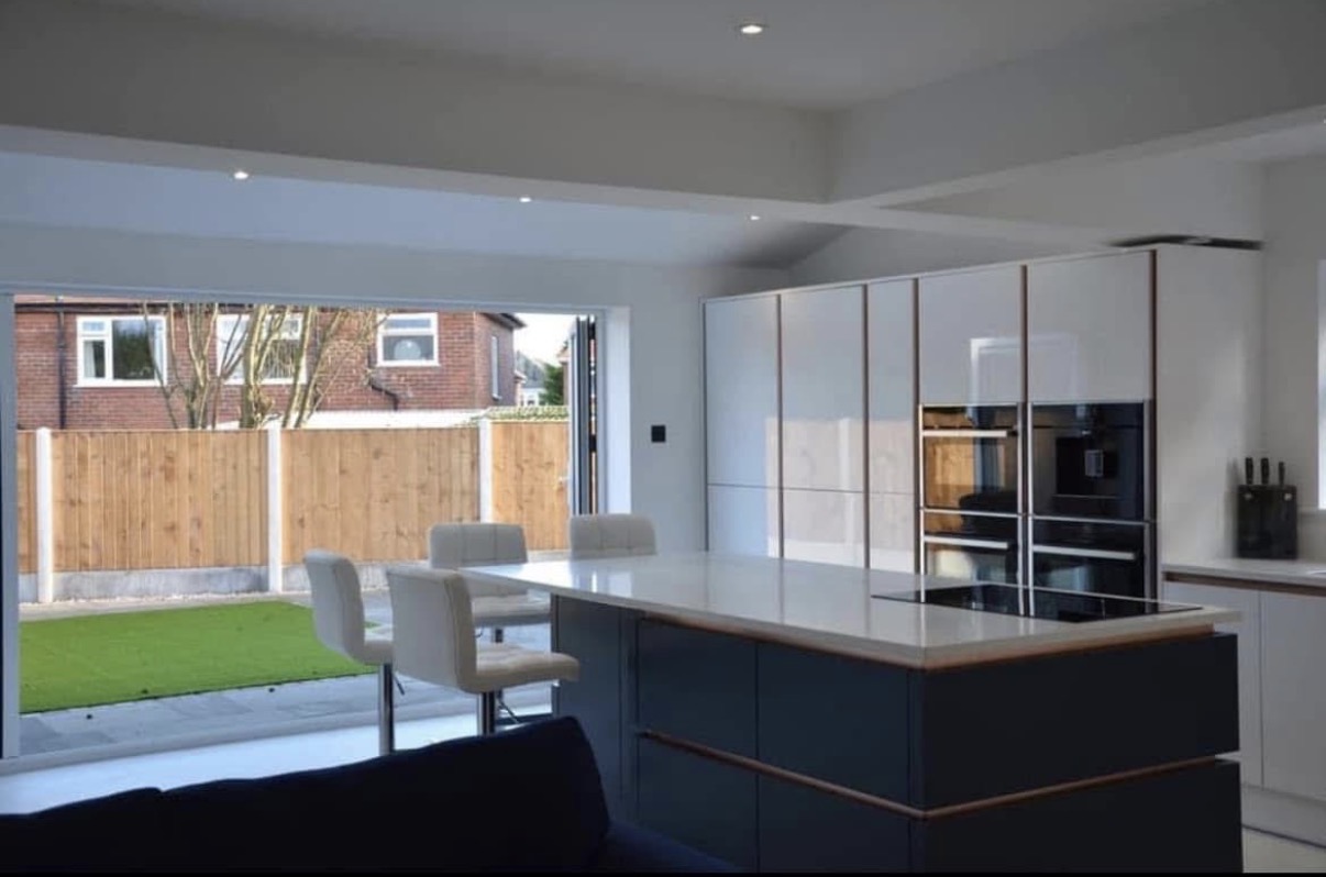 Handleless kitchen island in an extension with bifold doors to the garden